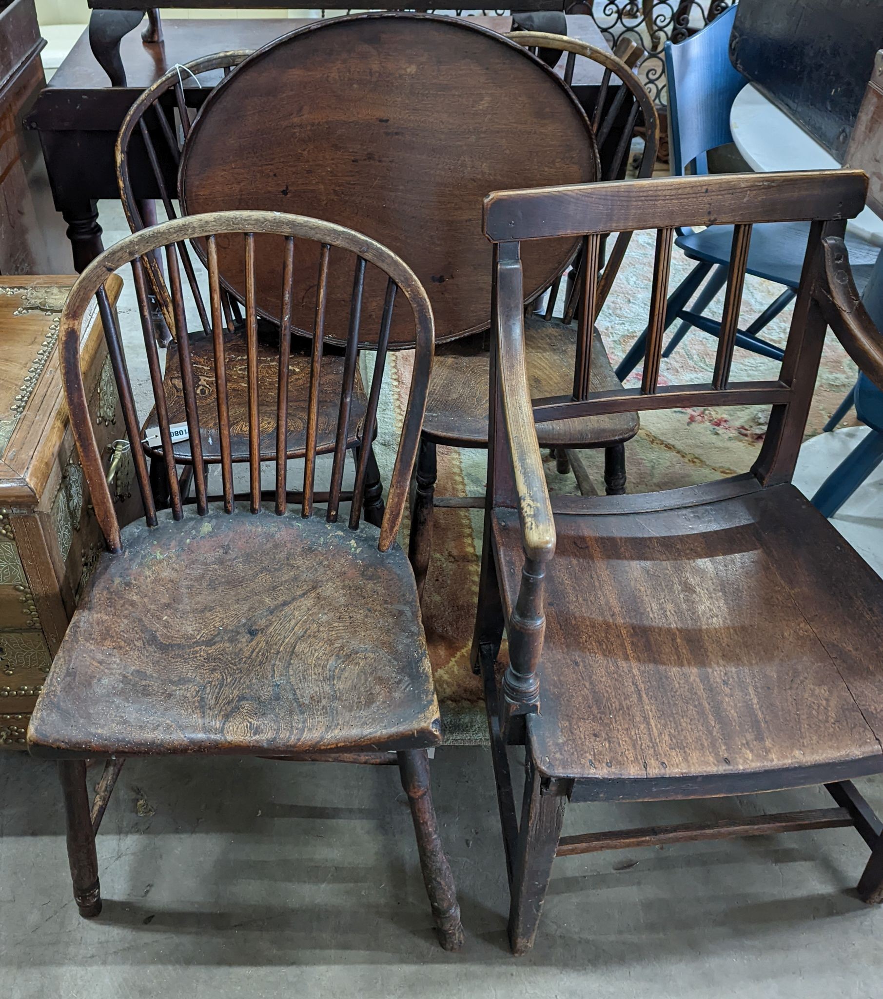 A 19th century elm and ash primitive Windsor comb back chair with traces of original paint, two other Windsor comb back chairs, a George III provincial elbow chair and an oval mahogany tea tray